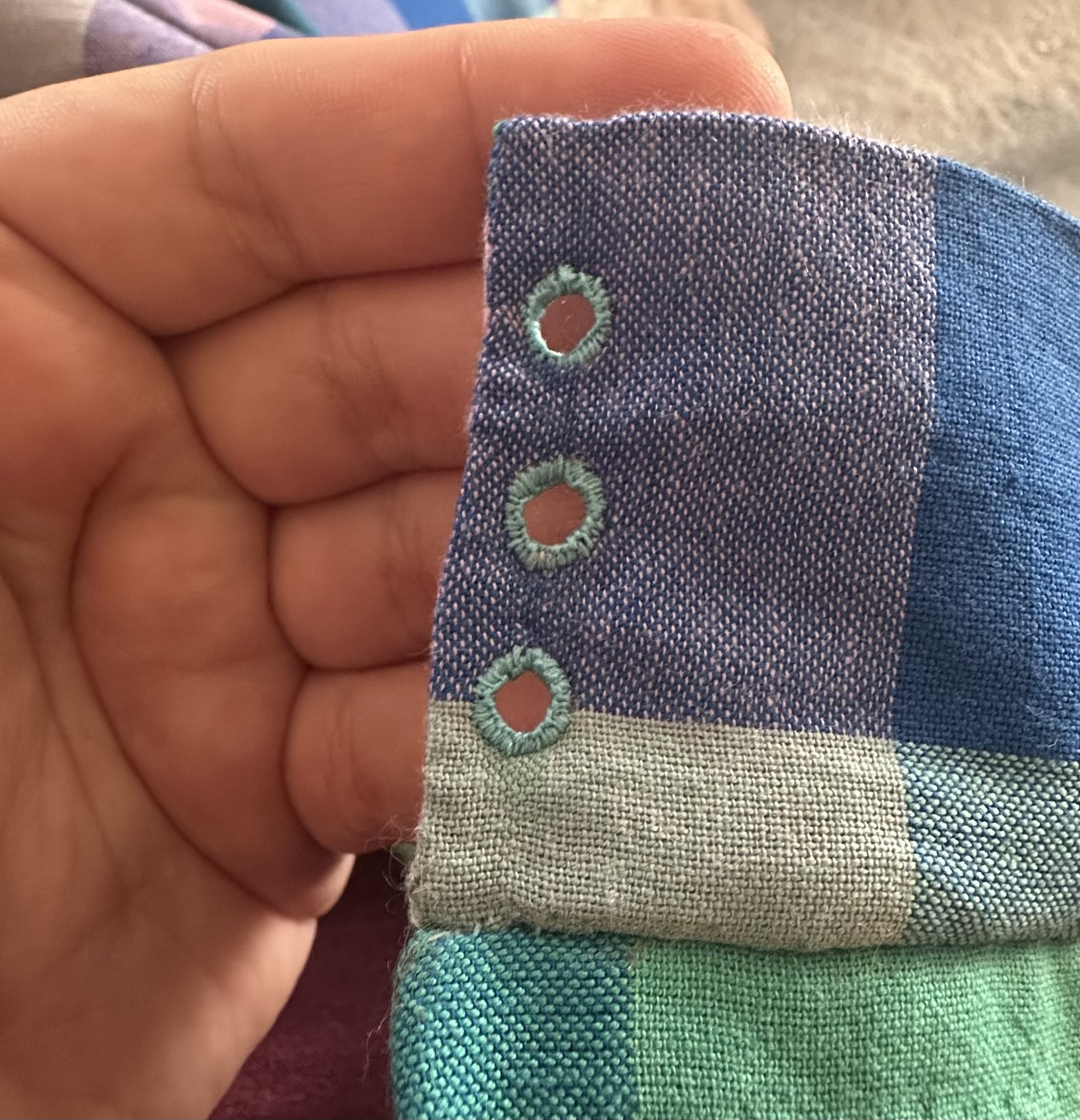 Hand-sewn eyelets on the edge of a waistband.